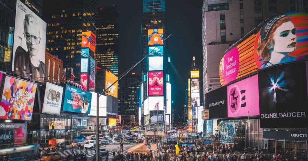 Times Square at night, illuminated with colorful billboards and crowds.