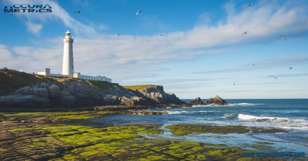 Île Vierge Lighthouse on a rocky coastline in Brittany, France, with cliffs and the ocean in the background.