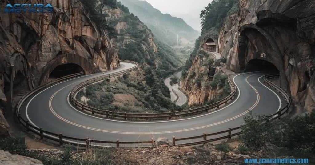 A breathtaking view of the Guoliang Tunnel Road carved into the side of a steep mountain, with sharp zigzags and dramatic cliffs in the Taihang Mountains.